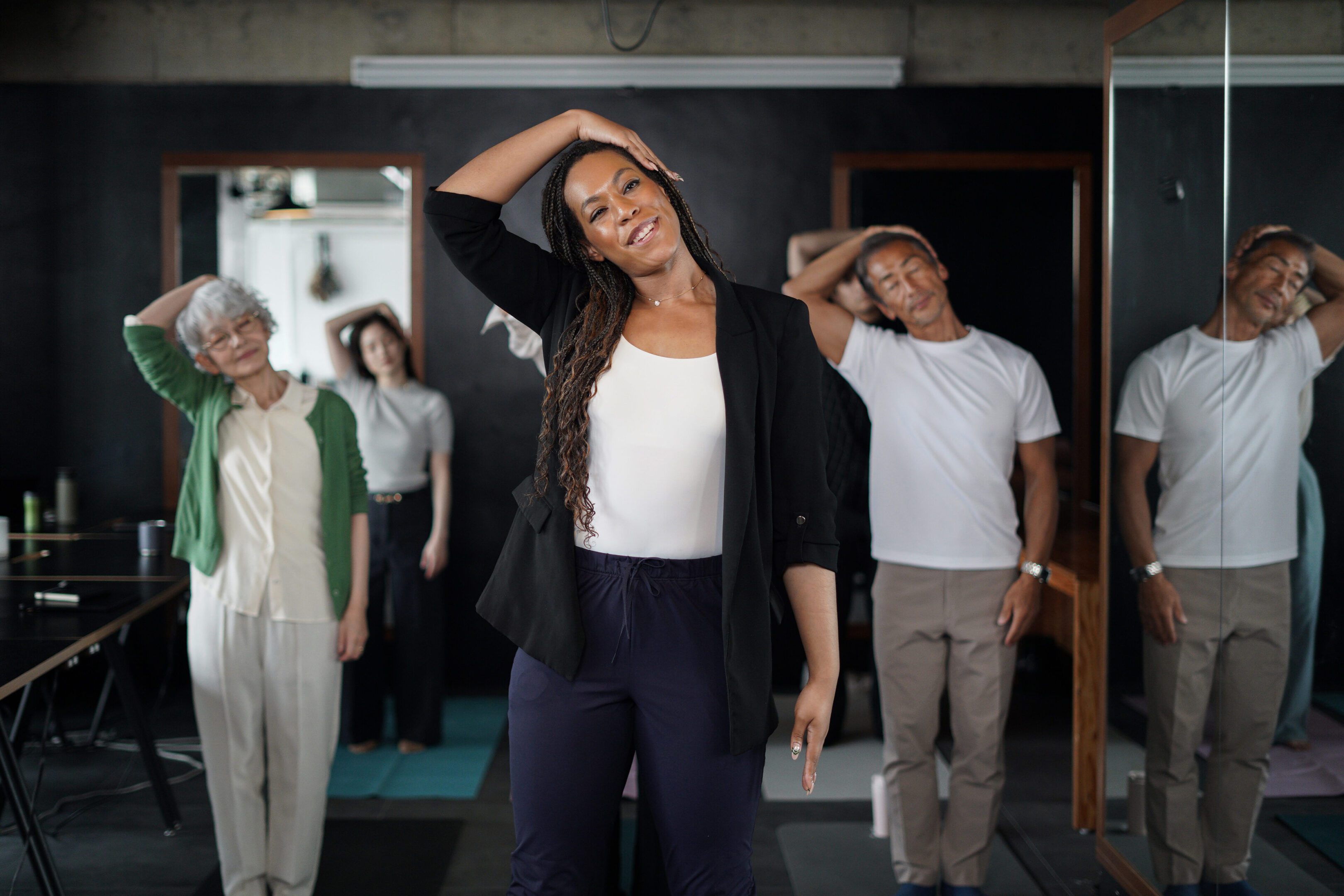 Group of multi-ethnic business people practicing office yoga and health exercise class in a modern office during work hours.